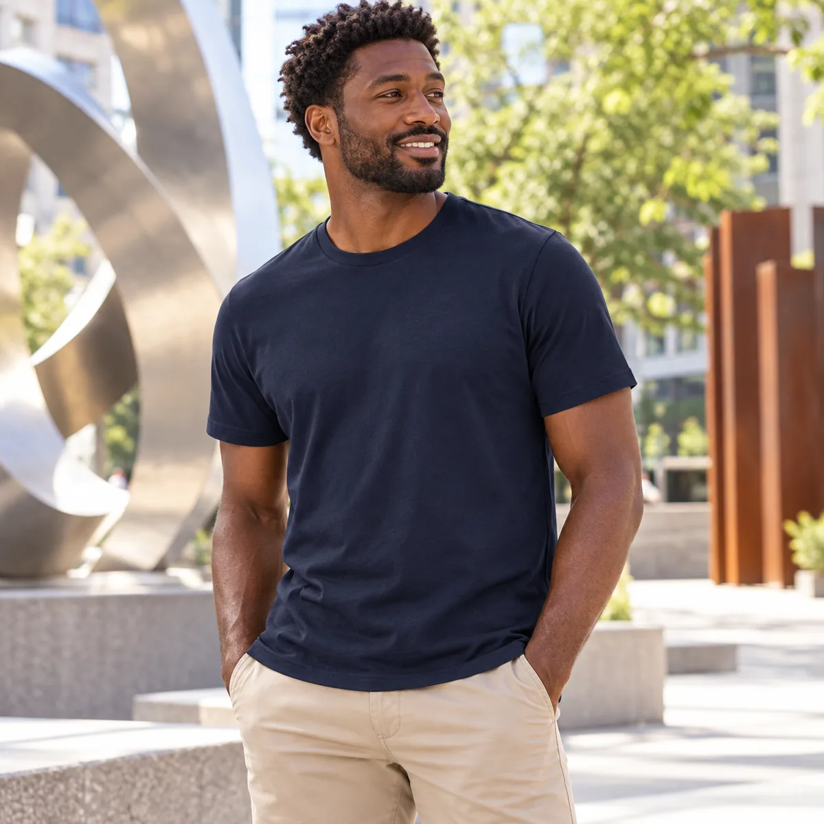 Man wearing a night sky navy Allmade organic cotton tee on an urban sculpture walk; blank front.