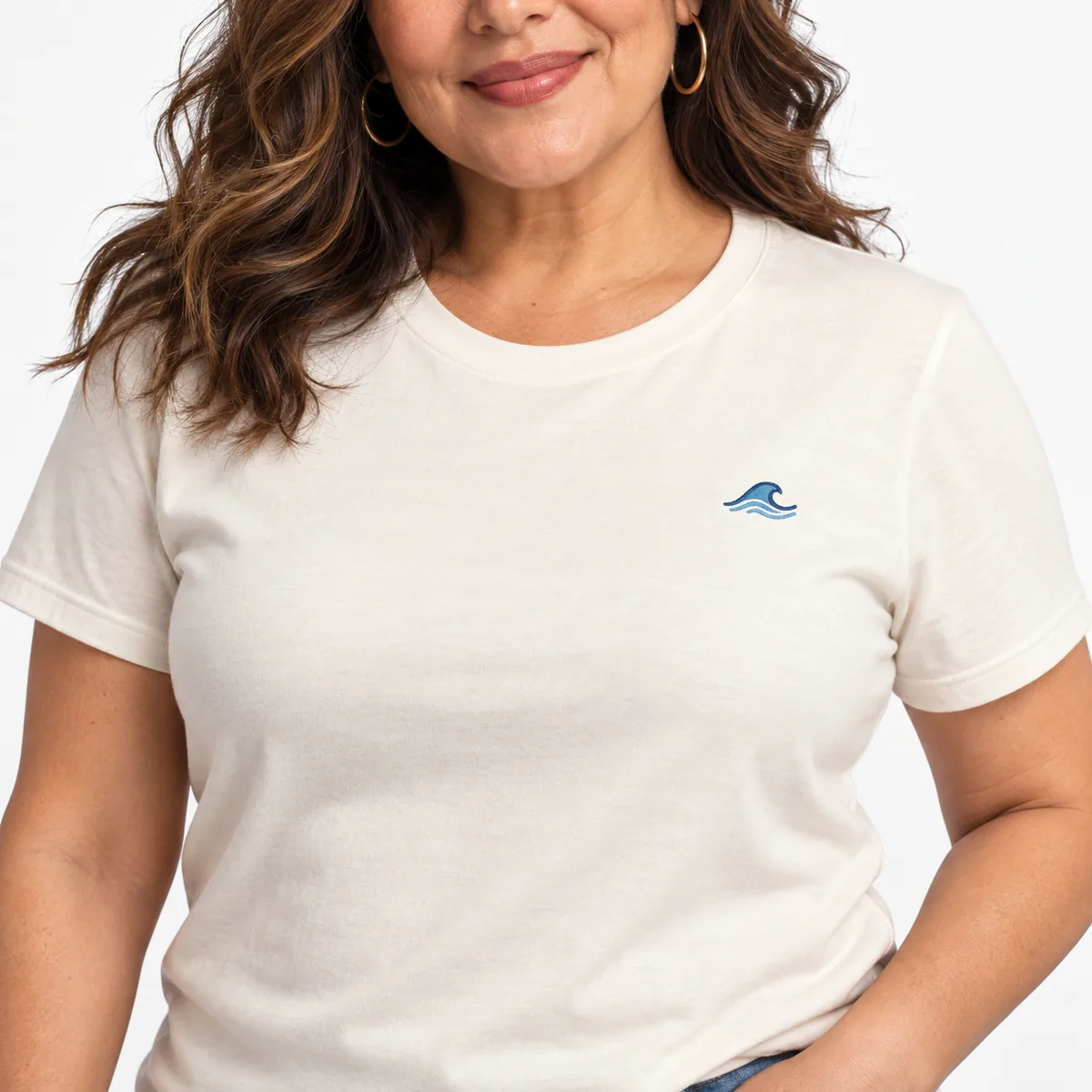 Close-up of a fictional wave emblem on a natural Bella + Canvas Ultra-Soft Jersey unisex T-shirt worn by a model.