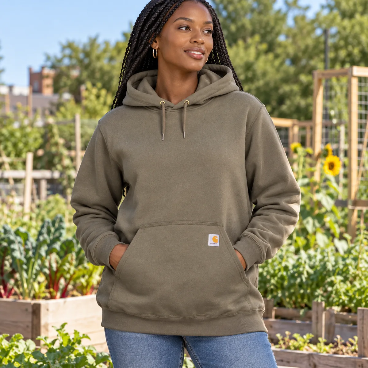 Woman wearing a moss Carhartt Loose-Fit Midweight Hoodie at a community garden.