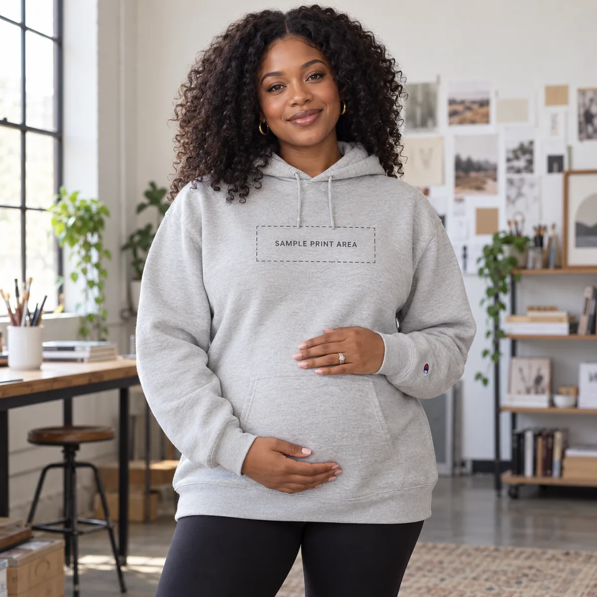 Pregnant Black woman wearing a stone grey hoodie with an illustrative chest print-area guide; dimensions are not verified.
