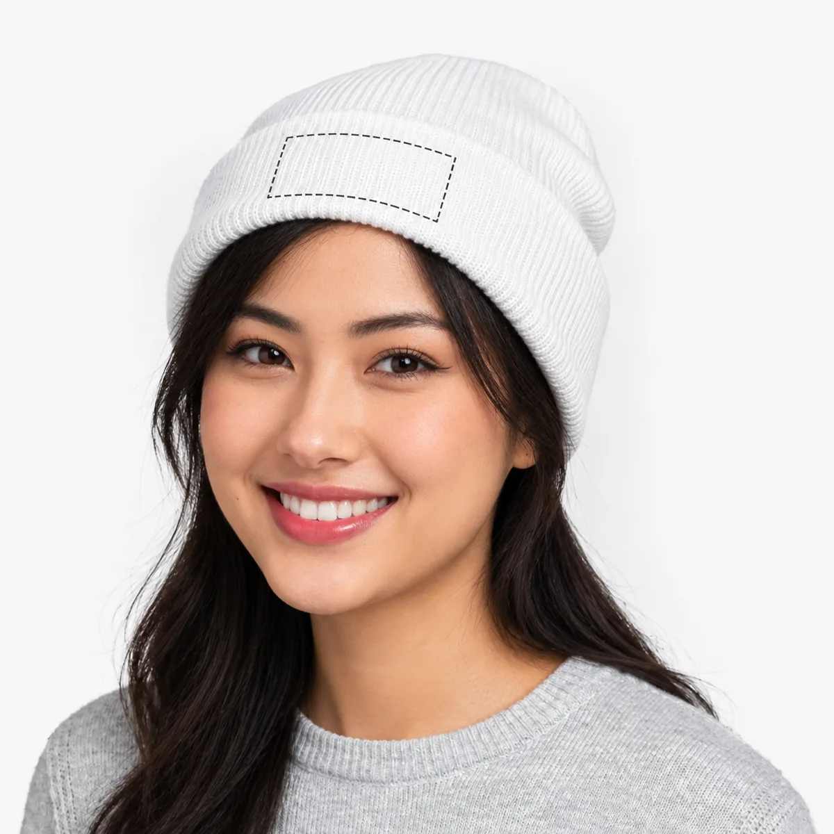Woman wearing a white cuffed beanie with an illustrative dashed decoration placement guide on the cuff; dimensions are not verified.