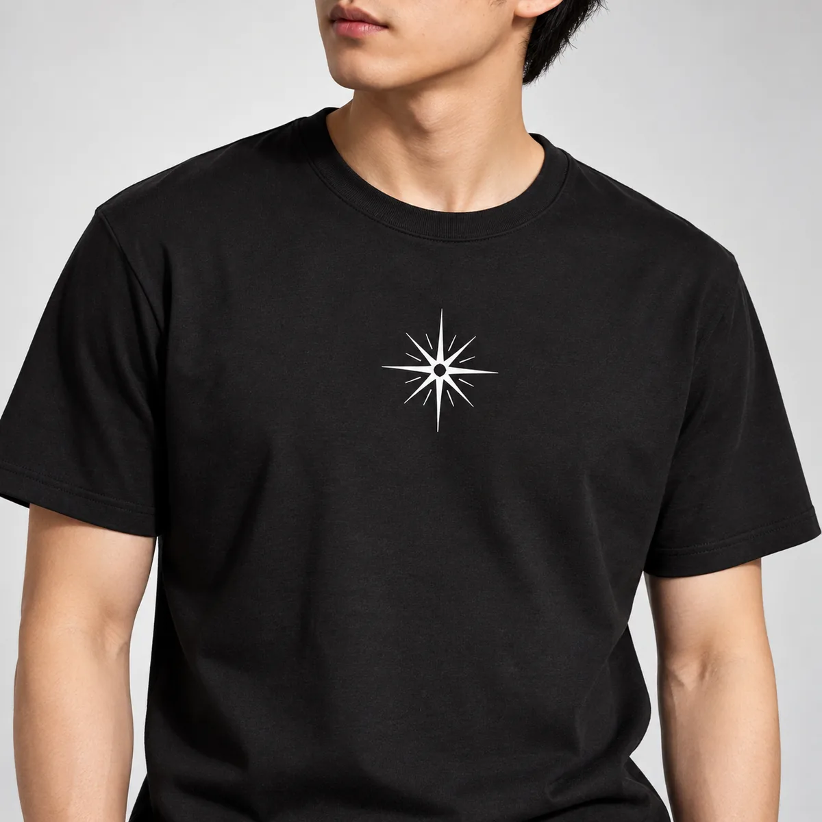 Close-up of a fictional starburst print on a black District Soft-Touch unisex T-shirt worn by a model.