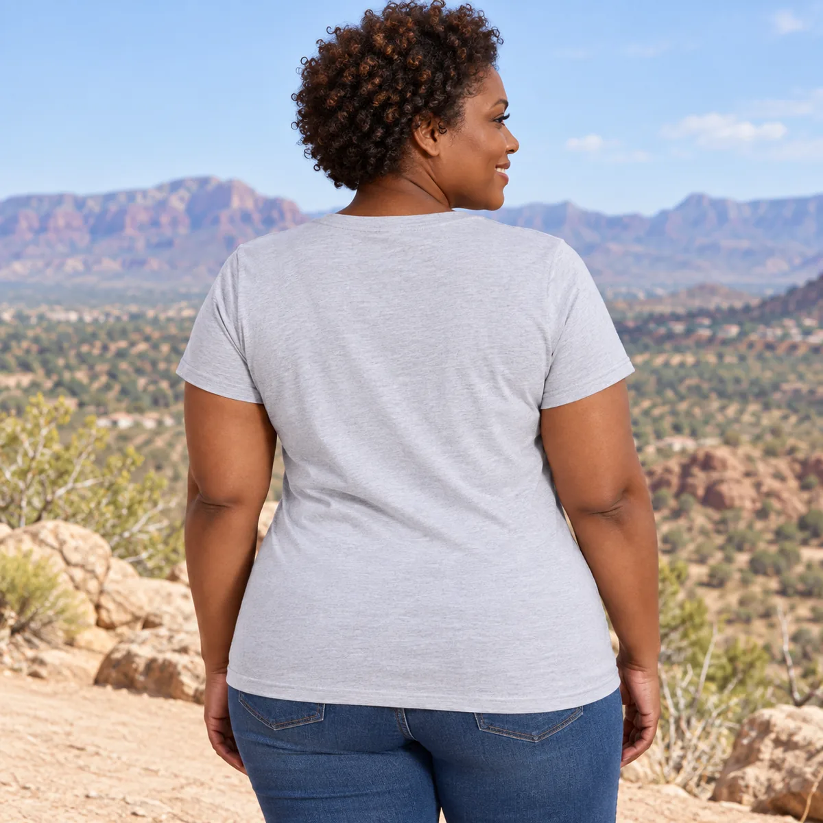 Woman wearing the light heather gray District Soft-Touch Women’s T-shirt, shown from behind at a desert overlook.