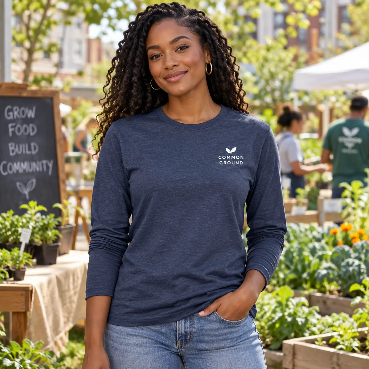 Woman wearing a heathered navy long-sleeve tee with fictional Common Ground sample branding at a community garden.