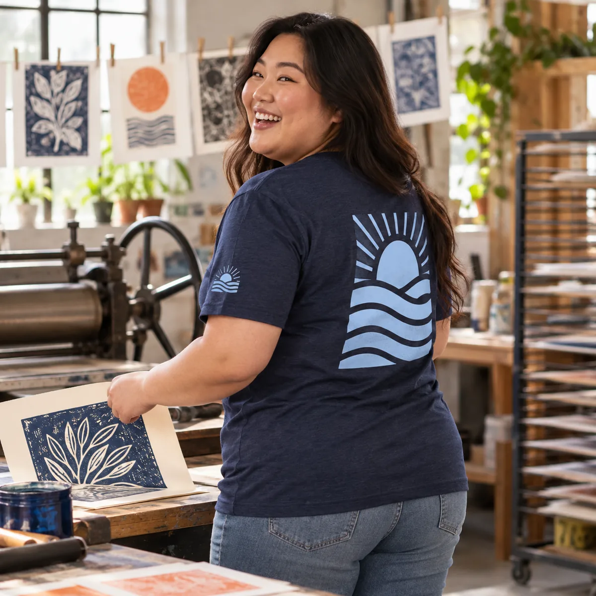 Model wearing a heathered navy District Very Important Tee with fictional coordinated front and back sample prints in a printmaking workshop.