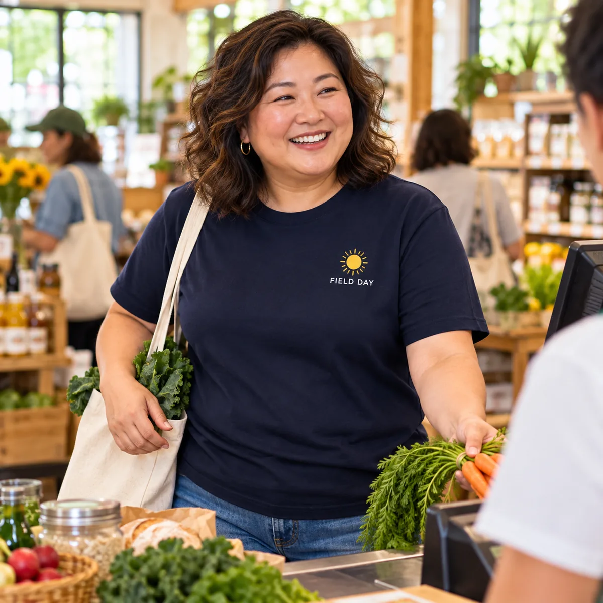 Model wearing a new navy District Very Important Tee with fictional Field Day chest branding at a food co-op.