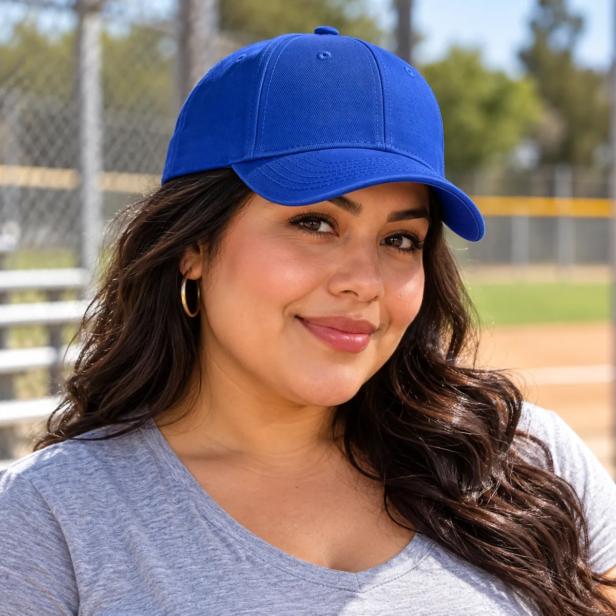 Woman wearing a royal blue blank Flexfit cap at a baseball field.