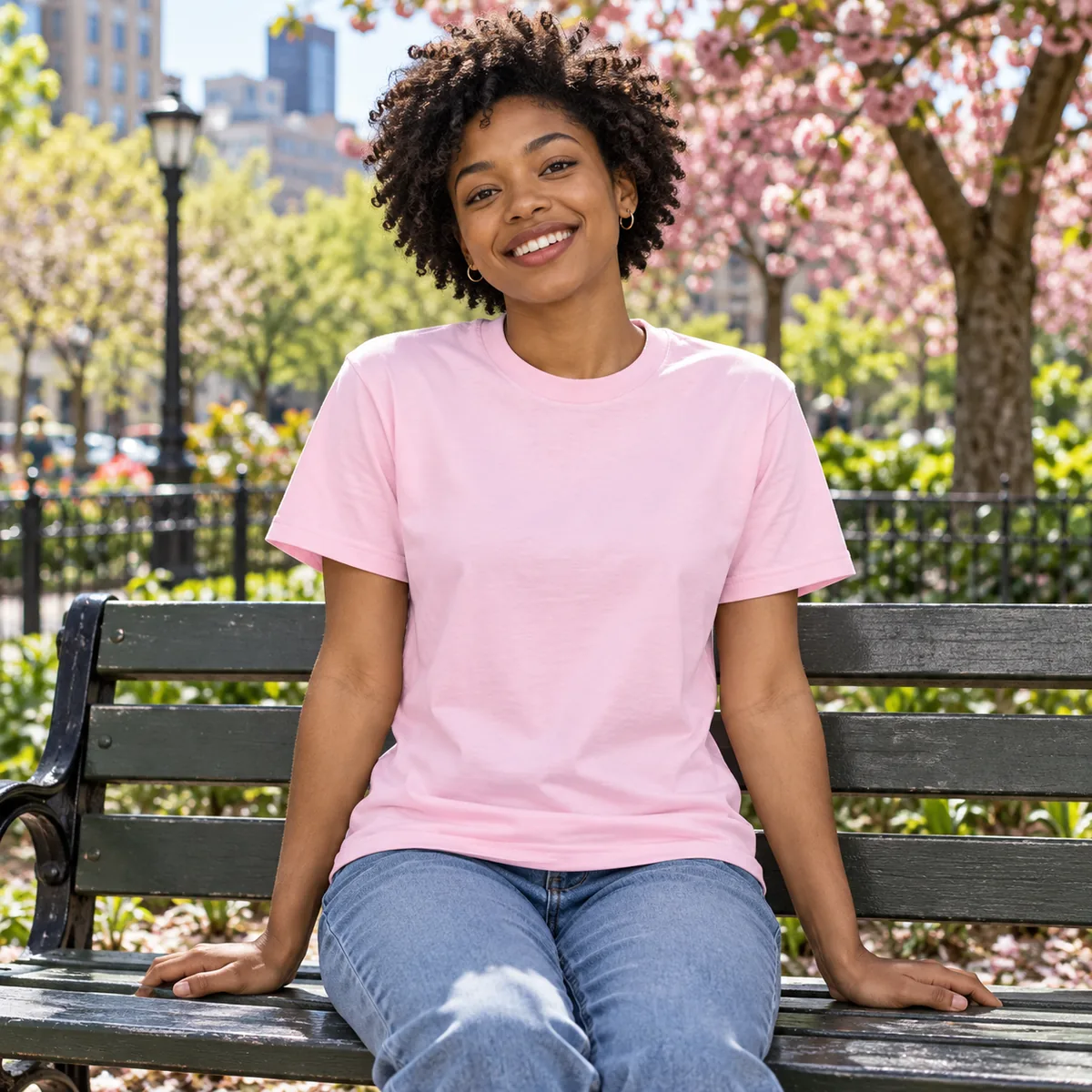 Model wearing the light pink Gildan Budget unisex T-shirt in a city park.