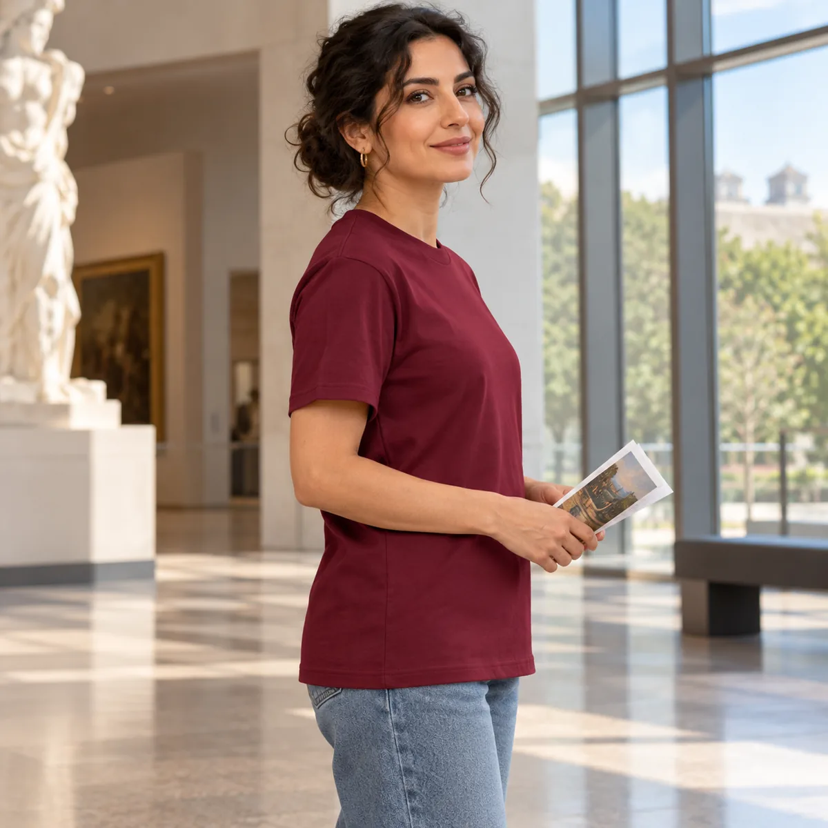 Side view of a model wearing the maroon Gildan Budget unisex T-shirt in a museum atrium.