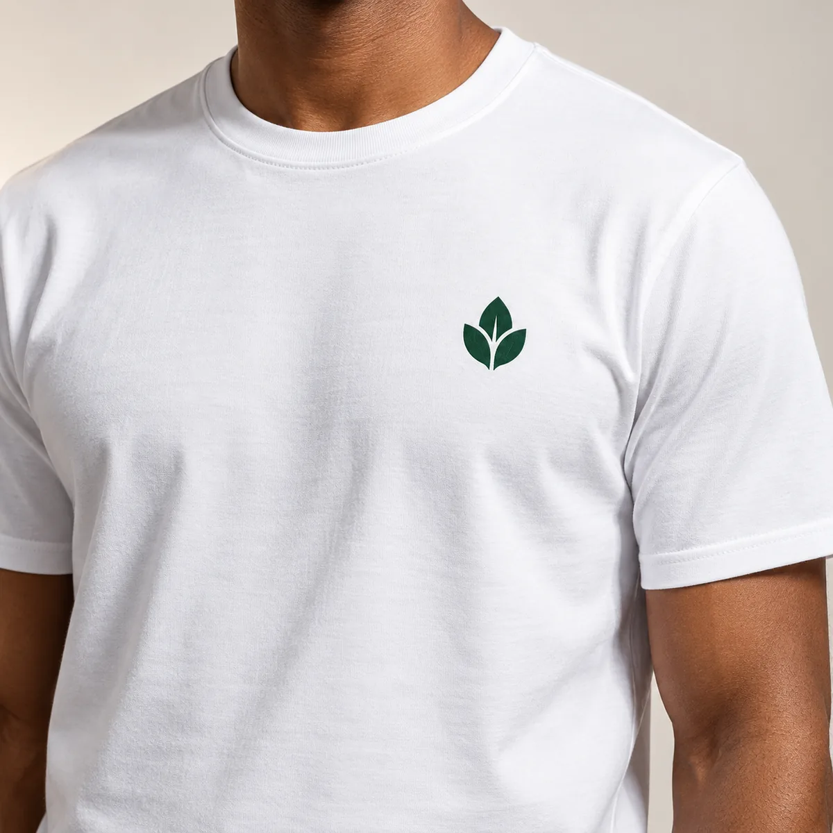 Close-up of a fictional leaf emblem printed on a white Gildan Budget unisex T-shirt worn by a model.