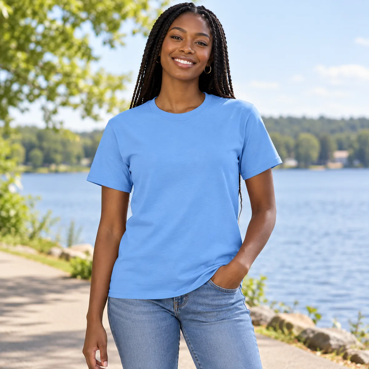 Woman wearing a Carolina Blue Gildan DryBlend tee on a lakeside path; blank front.