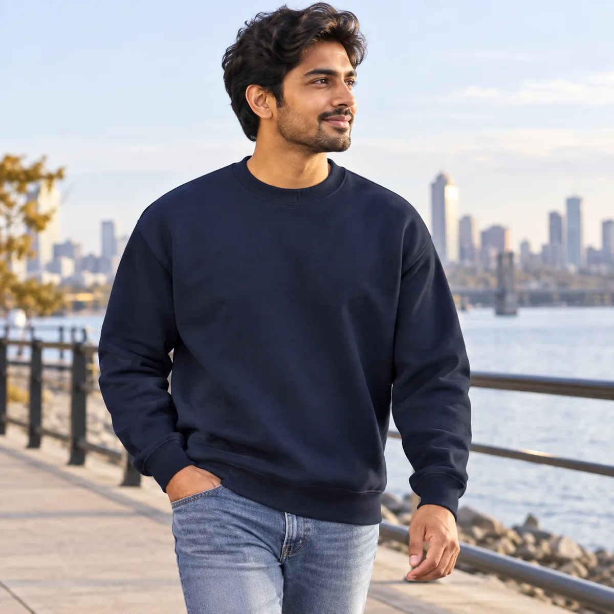 Man wearing a navy Gildan Heavy Blend sweatshirt on a waterfront path, shown in side view.