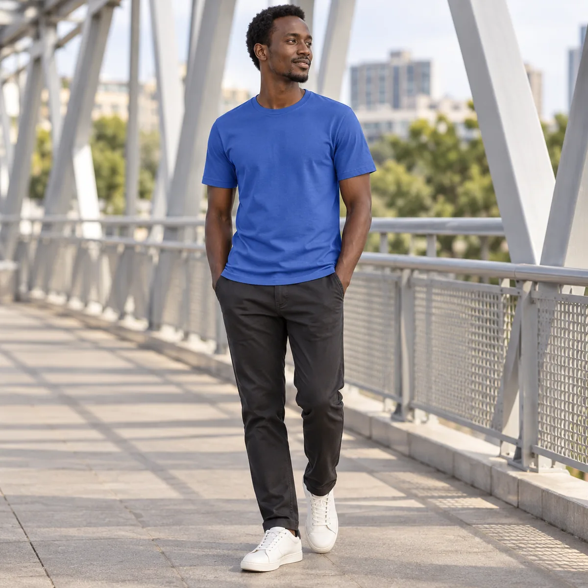 Model wearing a royal blue Gildan Softstyle unisex T-shirt on a pedestrian bridge.