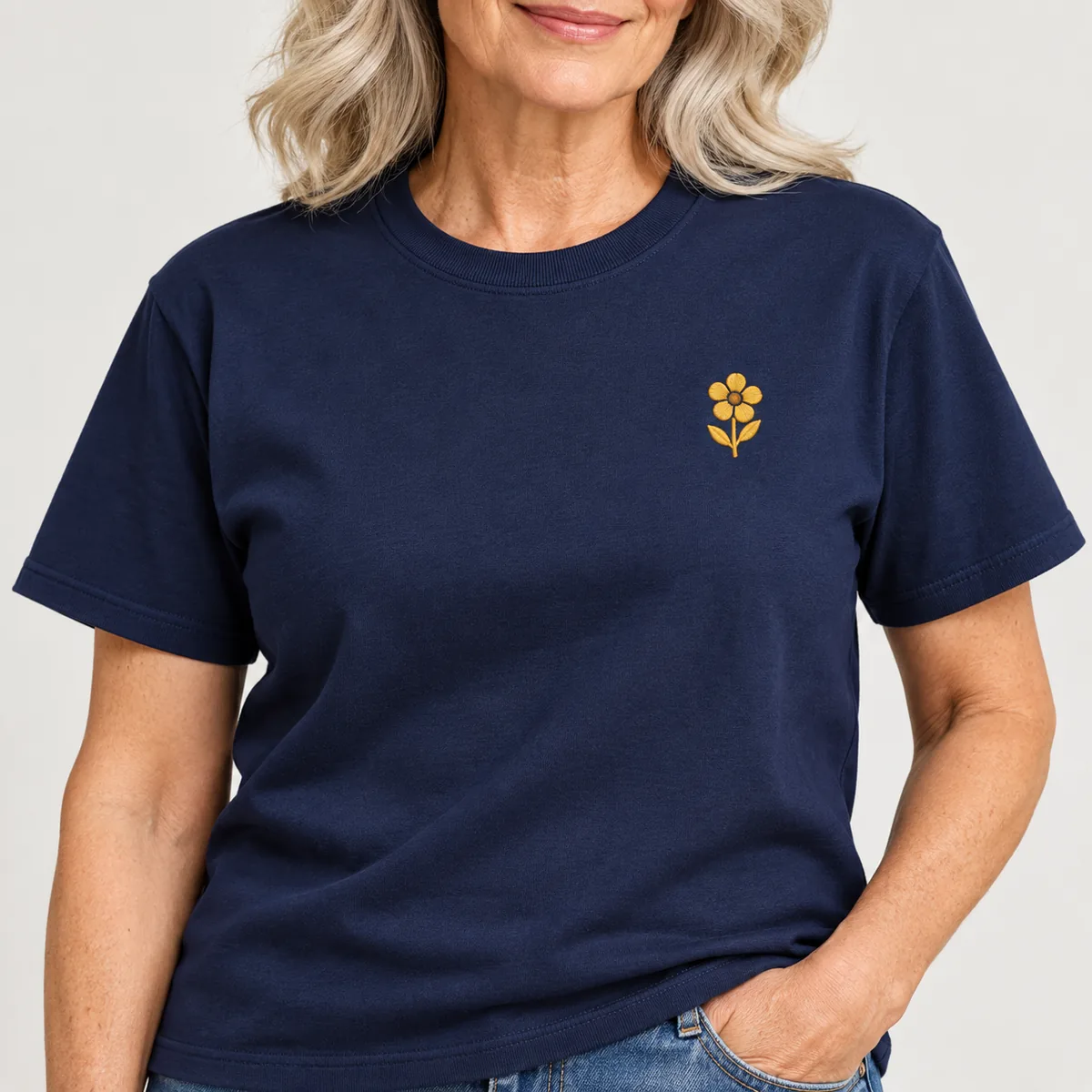 Close-up of a fictional flower emblem on a navy Gildan Ultra Cotton unisex T-shirt worn by a model.