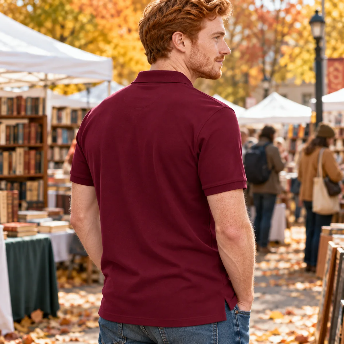 Man wearing a maroon JERZEES Piqué Polo Shirt at an autumn book fair, shown from the back.